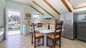 Una cocina con una mesa de comedor, sillas, un refrigerador y un ventanal con vistas al verdor.