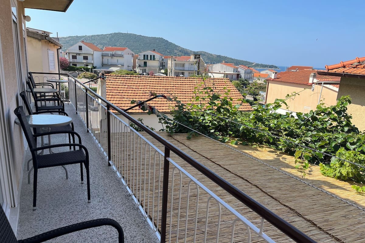 Un balcón con mobiliario exterior y vistas a una colina y edificios.
