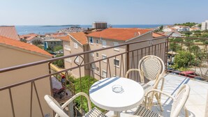 A balcony with a table and chairs overlooking a coastal town. - Apartments Jere Proto (Primosten)