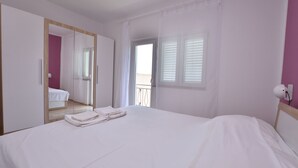 A bedroom with a large bed, a mirror, a window with blinds, and a balcony. - Apartments Jere Proto (Primosten)