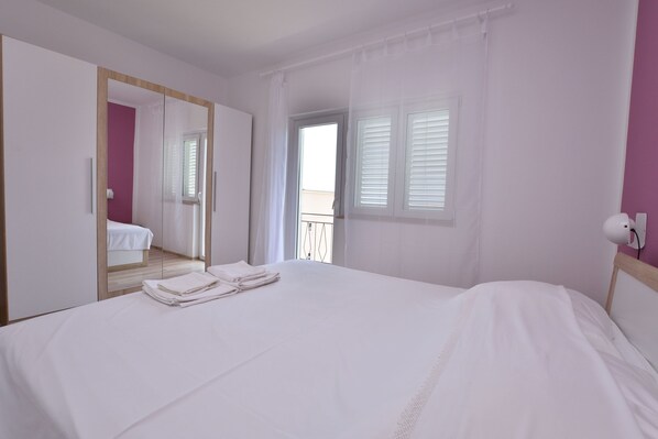 A bedroom with a large bed, a mirror, a window with blinds, and a balcony. - Apartments Jere Proto (Primosten)