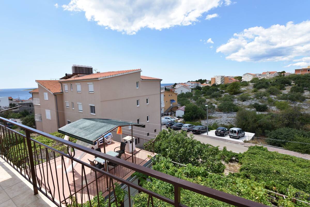 A residential building with a balcony, a covered outdoor seating area, and a view of the sea.