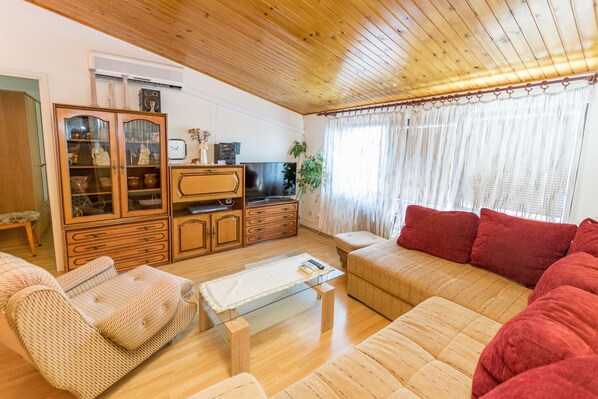 A living room with a wooden ceiling, a glass coffee table, a sofa, and a cabinet with glass doors. - Apartments Jere Proto (Primosten)