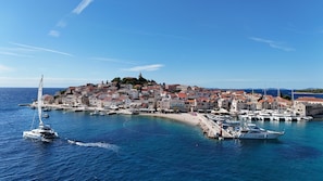 A coastal town with historic buildings, a marina with boats, and a clear blue sky.