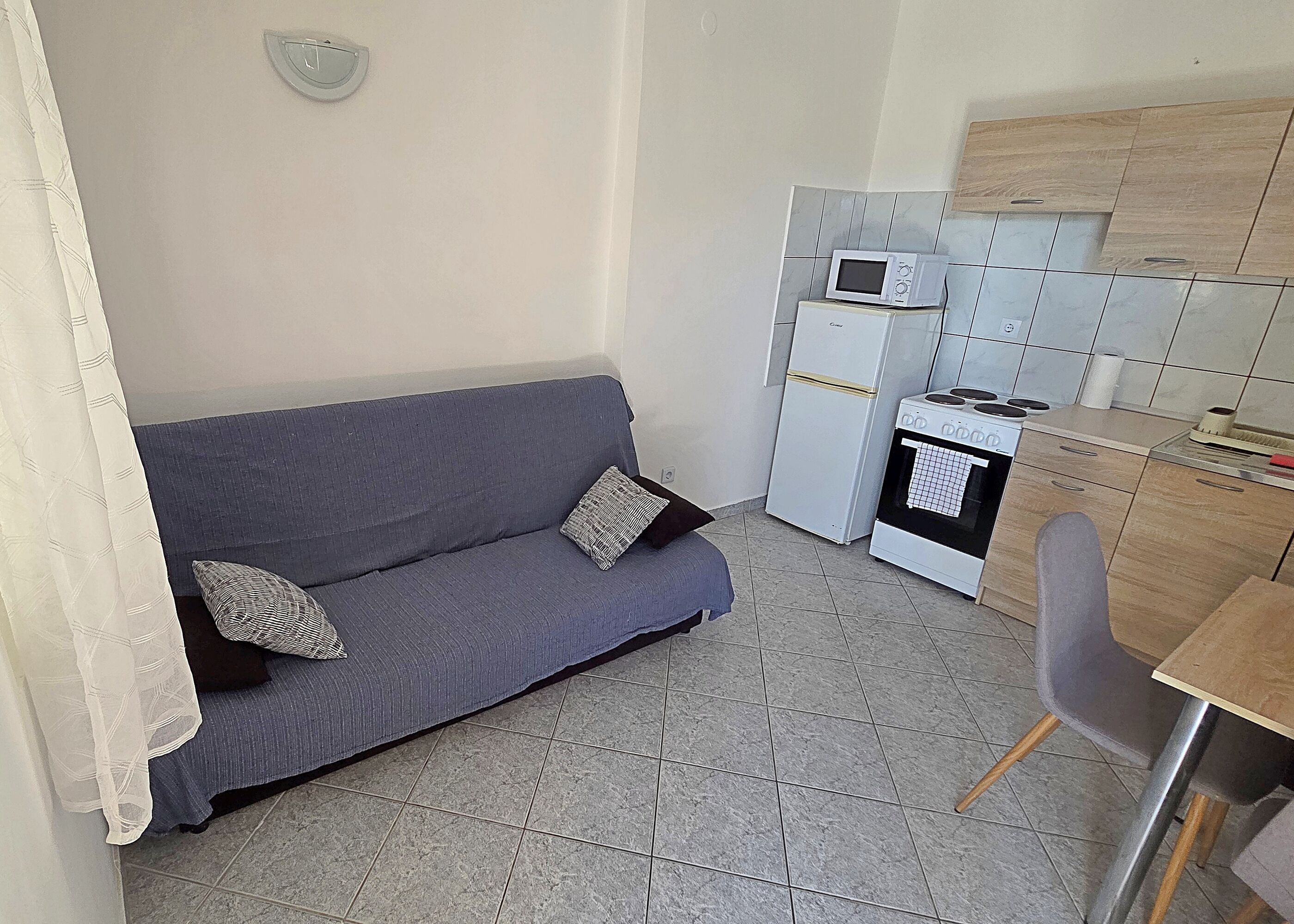 Un espace de vie compact comprenant un canapé, une kitchenette et un coin repas.