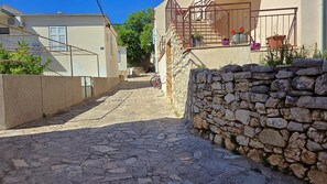 Uma rua de paralelepípedos estreita, ladeada por paredes de pedra e edifícios com varandas.