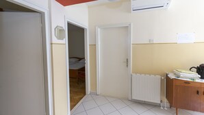 Een gang met een radiator, een houten kast en een bed op de achtergrond.