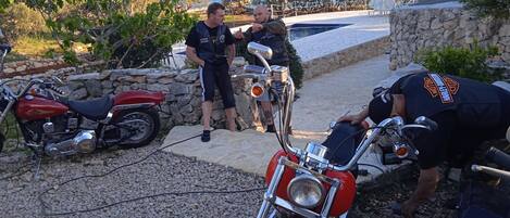 A stone wall, a red motorcycle, and a person wearing a Harley-Davidson shirt.