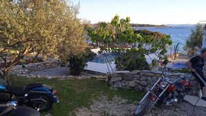 Une allée gravillonnée, un mur de pierres et une moto garée.