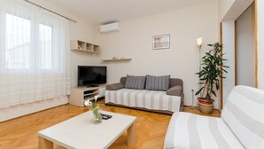A living room with a sofa, a TV, a coffee table, and a potted plant. - Apartment Antonija (Primosten)