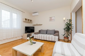 A living room with a sofa, a TV, a coffee table, and a potted plant. - Apartment Antonija (Primosten)