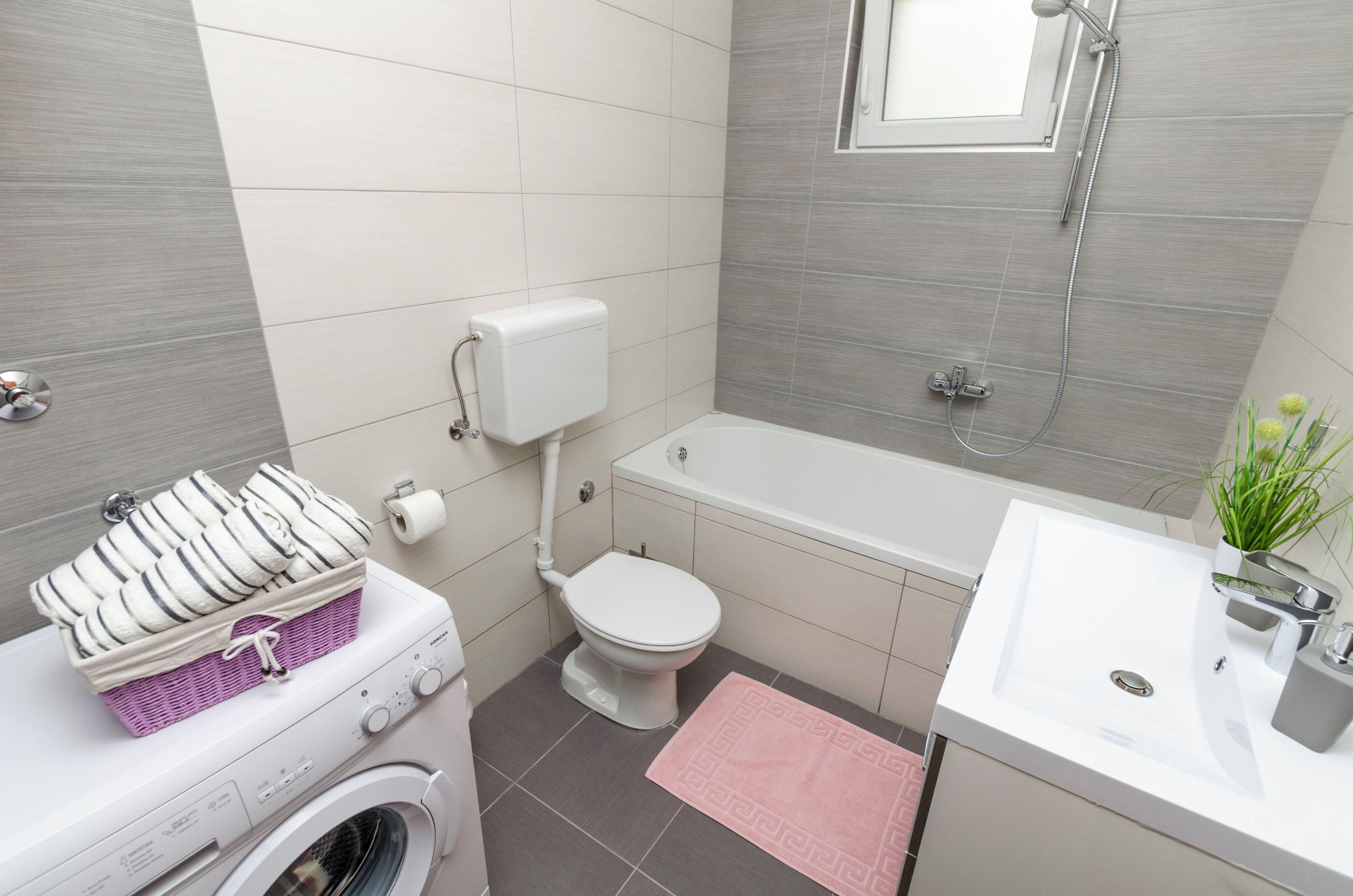 A compact bathroom with a washing machine, a toilet, a bathtub, and a sink.