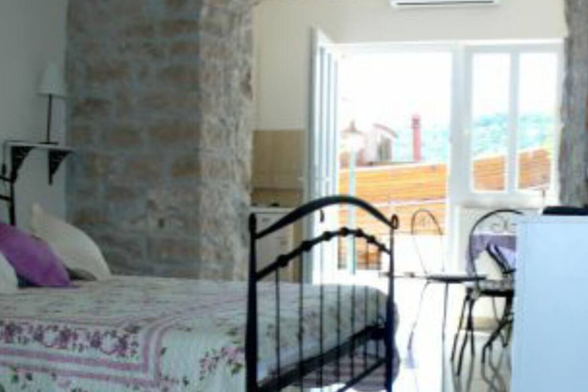 A bedroom with a bed, a desk, and a chair. There is a window with a view of the outside.