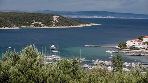 Un port de plaisance situé sur la côte, avec des bateaux, une plage de sable et un paysage vallonné en arrière-plan.