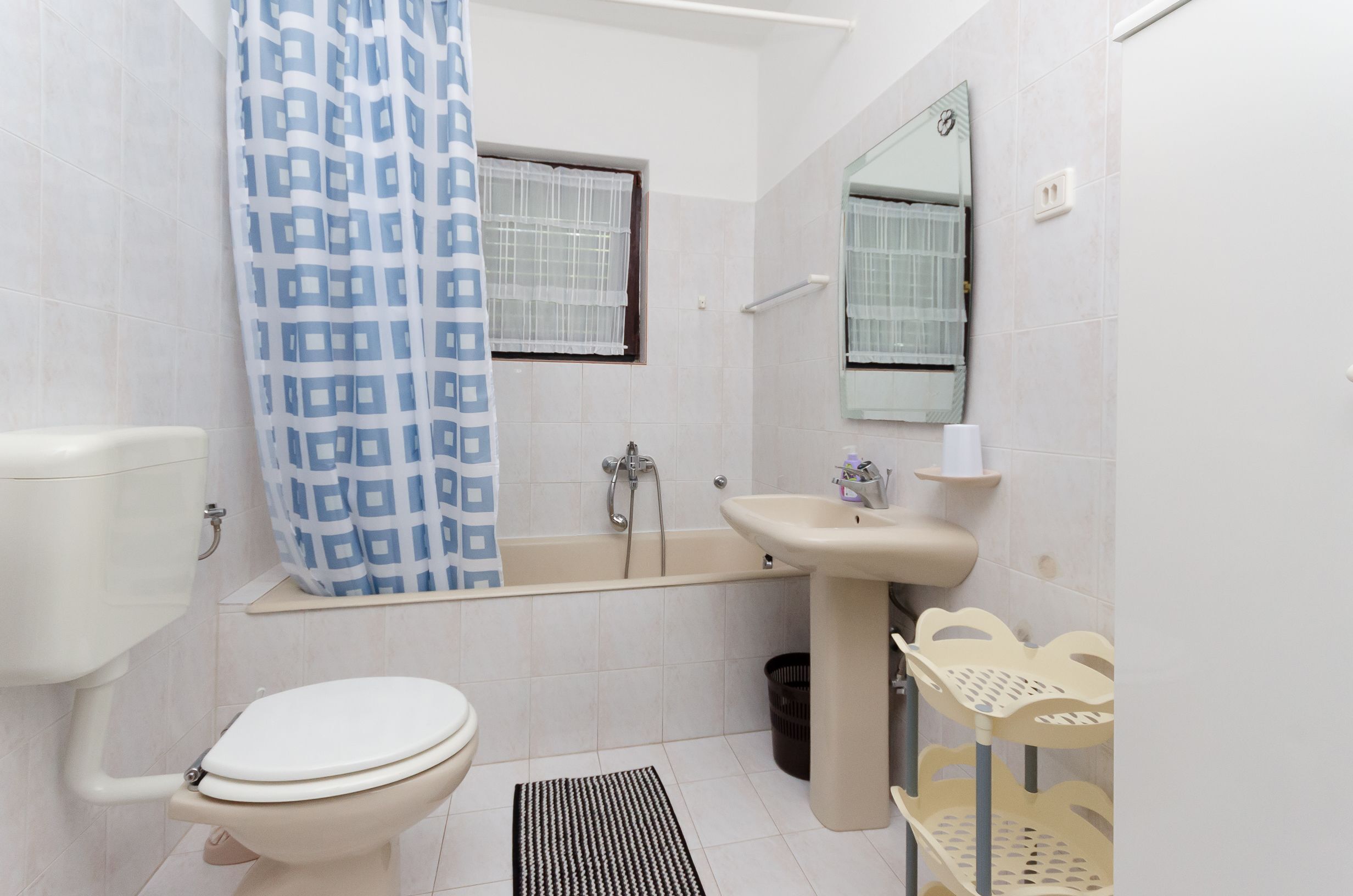 A bathroom with a toilet, bathtub, sink, and a shower curtain.