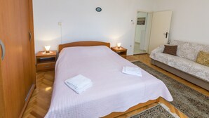 A neatly arranged bedroom with a bed, bedside tables, a sofa, and a chandelier. - Apartment Linda (Primosten)