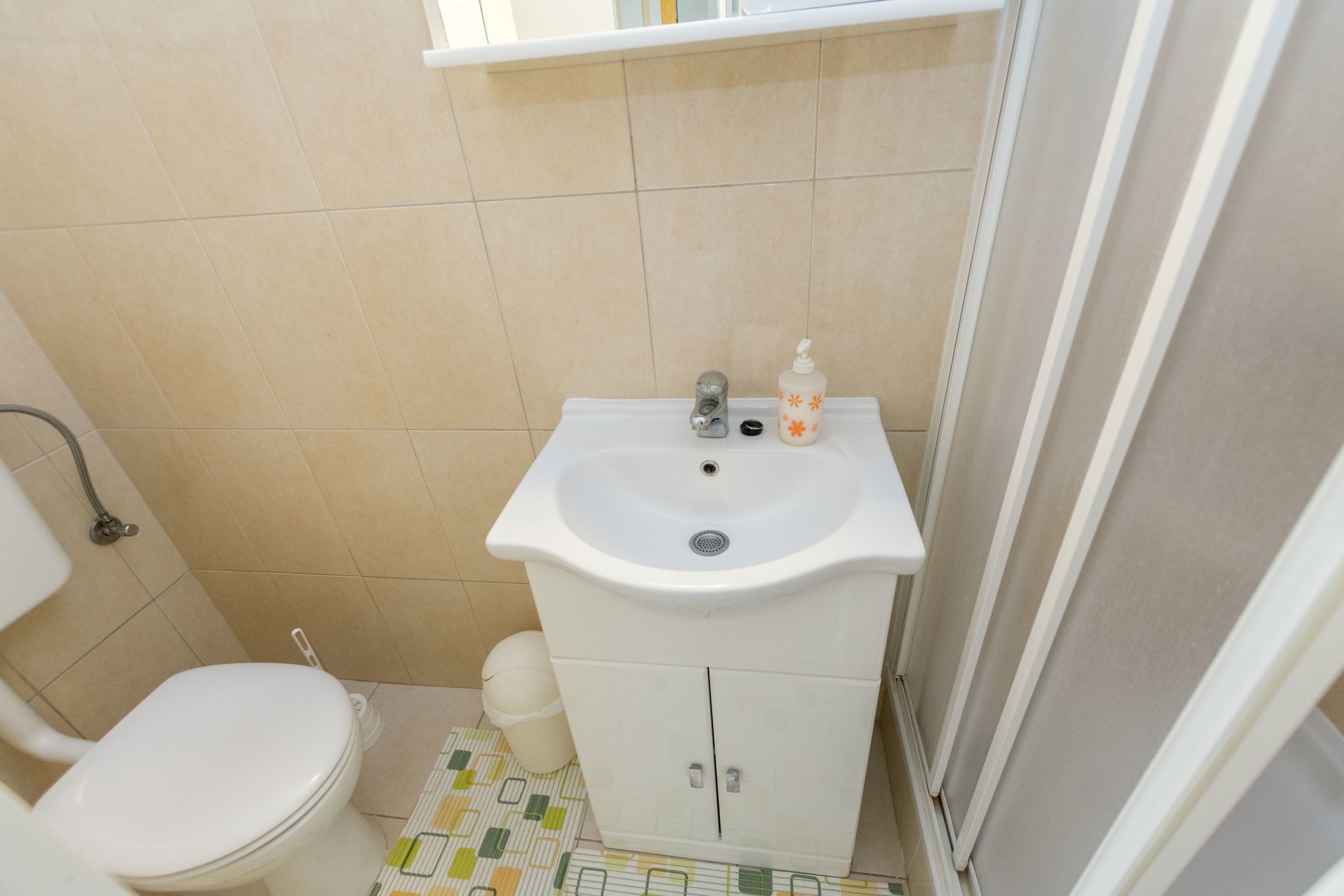 Ein kleines Badezimmer mit einem weißen Waschbecken, einer Toilette und einem Schrank.