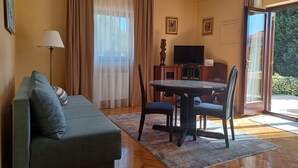 A living room with a sofa, a dining table with chairs, a TV, and a chandelier. - Apartments Stana (Zadar)