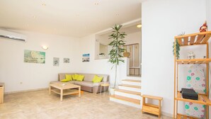 A modern living room with a sofa, coffee table, and a staircase leading to an upper level. - Apartments Dragana (Lokva Rogoznica)