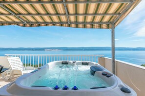 A hot tub with a view of the sea, a white chair, and a covered area. - Apartments Dragana (Omis)