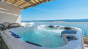 A hot tub with jets, a table with chairs, and a view of the sea. - Apartments Dragana (Lokva Rogoznica)