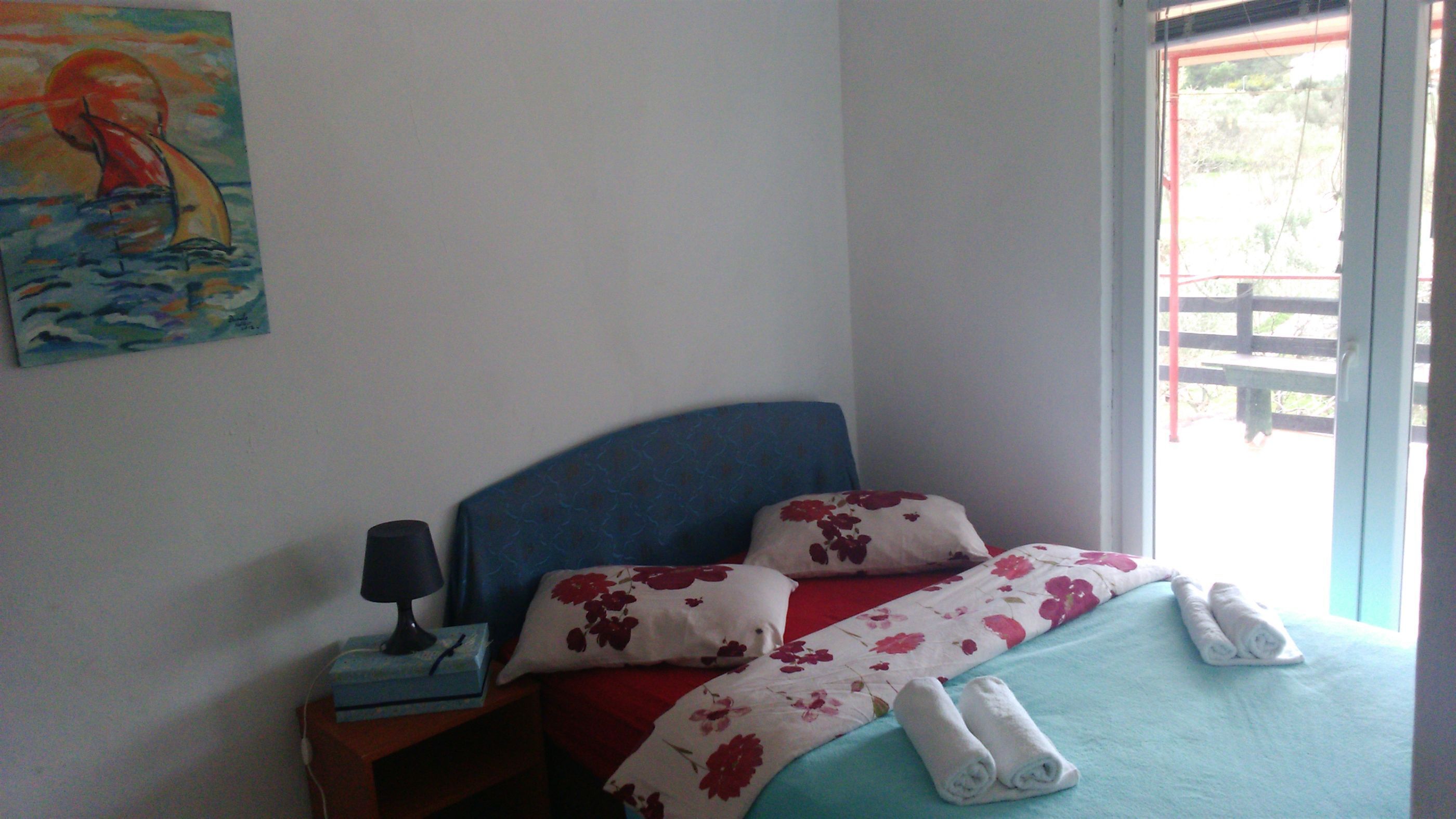 Une chambre à coucher avec un lit, des oreillers, une table de chevet, une lampe et un tableau au mur.