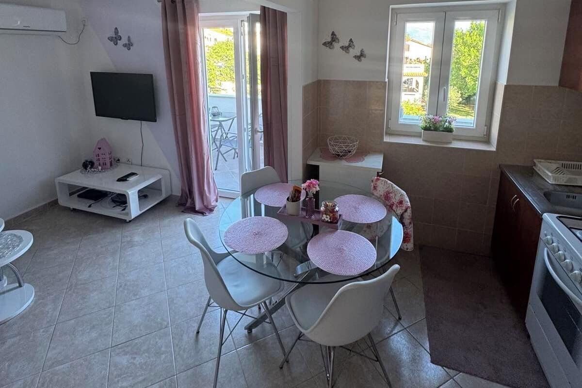 A compact kitchen with a dining area, a TV, and a window with a view.