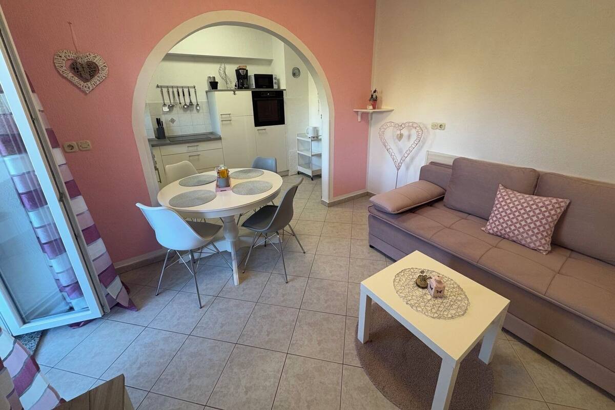 A cozy living room with a sofa, a coffee table, and a dining area with chairs and a table.