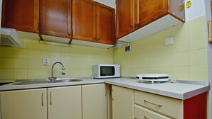 Une cuisine avec des meubles de rangement en bois, un micro-ondes blanc et une balance sur le plan de travail.