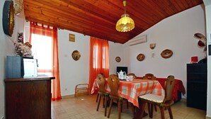 Un coin repas avec un plafond en bois, une table recouverte d’une nappe à carreaux rouges et blancs, et des chaises en bois.