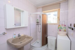 A bathroom with a shower, sink, and a window. - Apartment Kralj (Selce)