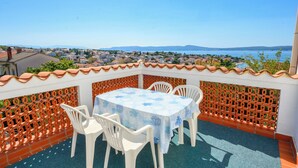 A terrace with a table and chairs, overlooking a coastal town and sea. - Apartment Kralj (Selce)