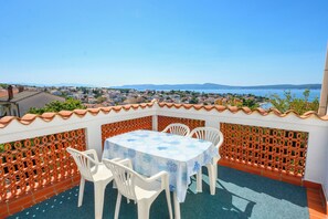 A terrace with a table and chairs, overlooking a coastal town and sea. - Apartment Kralj (Selce)