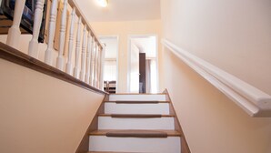 Eine Treppe mit Holzbalken und weißen Geländern, die zu einem Innenraum führt.