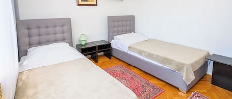 Una habitación doble con dos camas, una mesita de noche, una lámpara y dos cuadros en la pared.