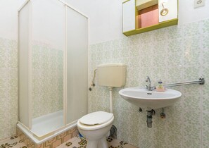 A bathroom with a shower, toilet, sink, and a mirror above the sink. - Apartments Mario (Omis)