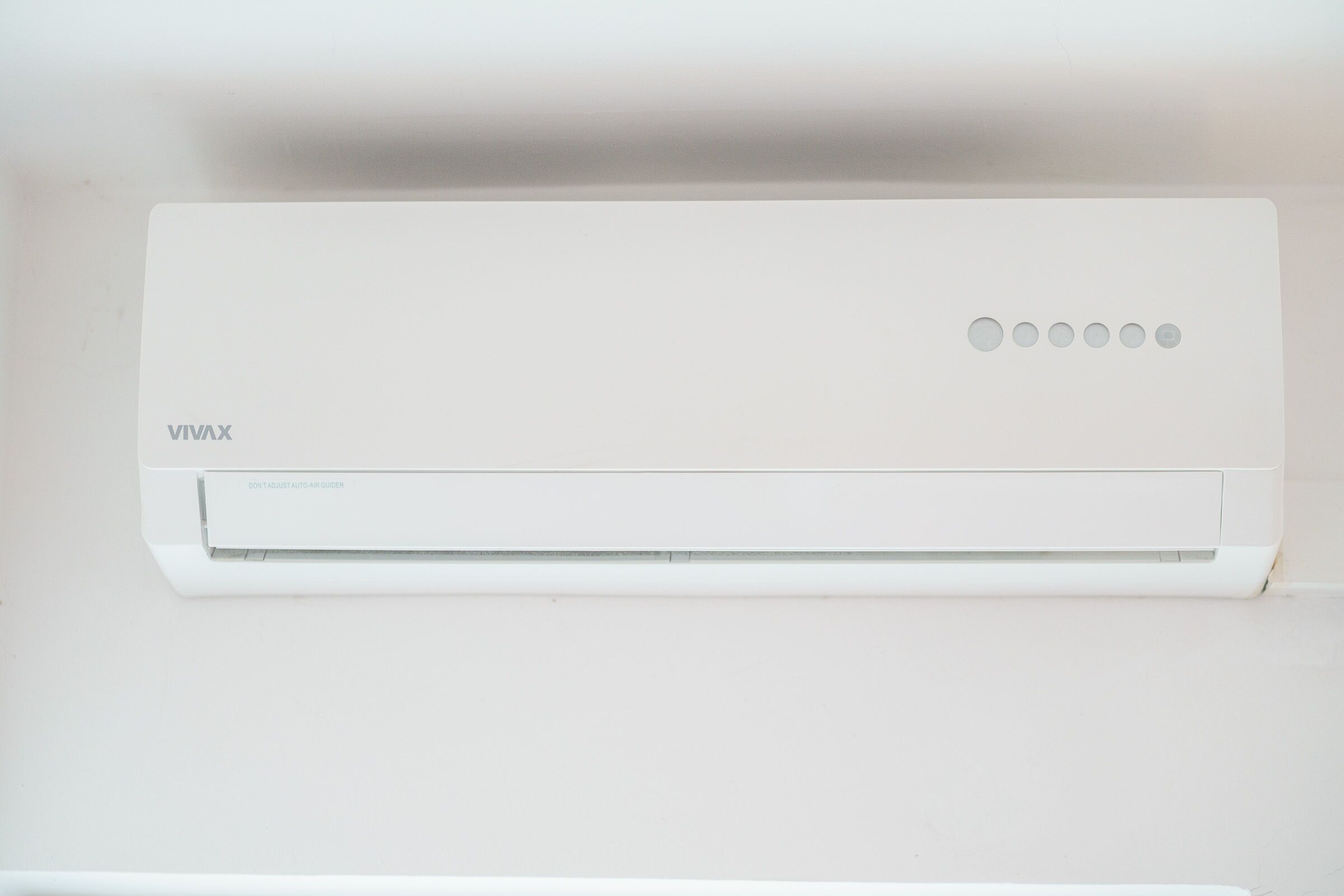 Een witte airconditioning met het merk 'VIVAX' en een bedieningspaneel met vijf knoppen.