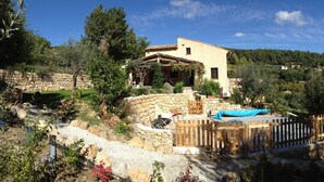 A stone house with a patio, surrounded by trees and a wooden fence. - L'Estuve Provençale (Bargemon)