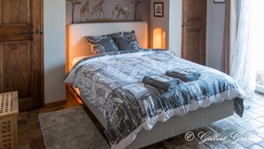 A bedroom with a bed, wooden doors, a wall mural, and a window with curtains. - L'Estuve Provençale (Bargemon)