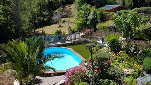 A swimming pool surrounded by lush greenery and a stone wall. - L'Estuve Provençale (Bargemon)