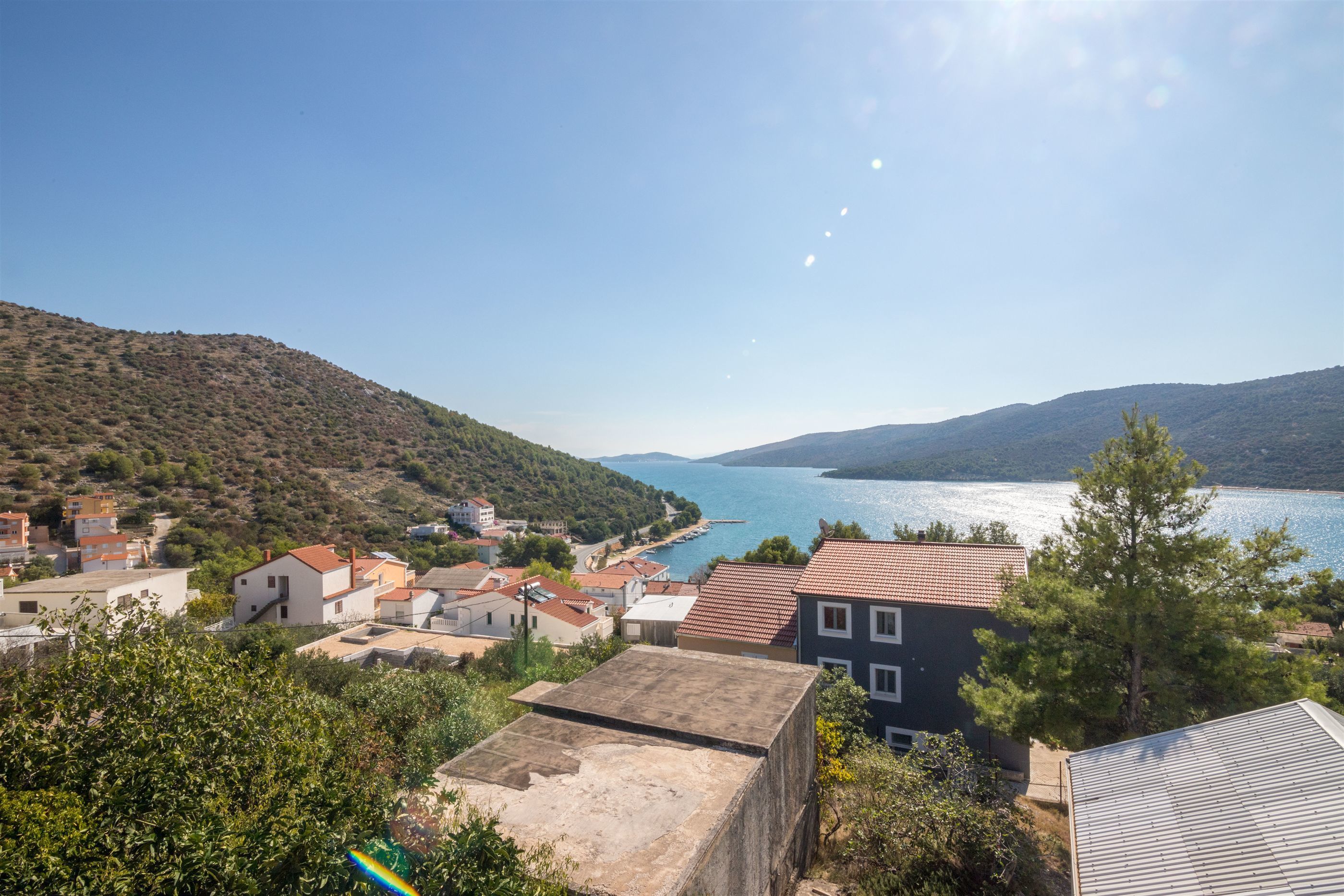 A coastal town with buildings overlooking a bay, surrounded by hills.