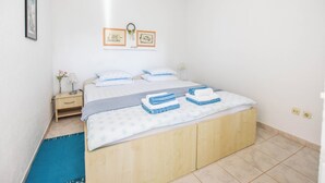 A bedroom with a bed, bedside table, and wall-mounted artwork. - Apartment Ivan (Veli Rat)