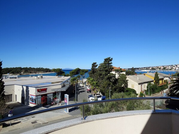 A coastal view with a clear sky, a marina, and buildings with visible signage.