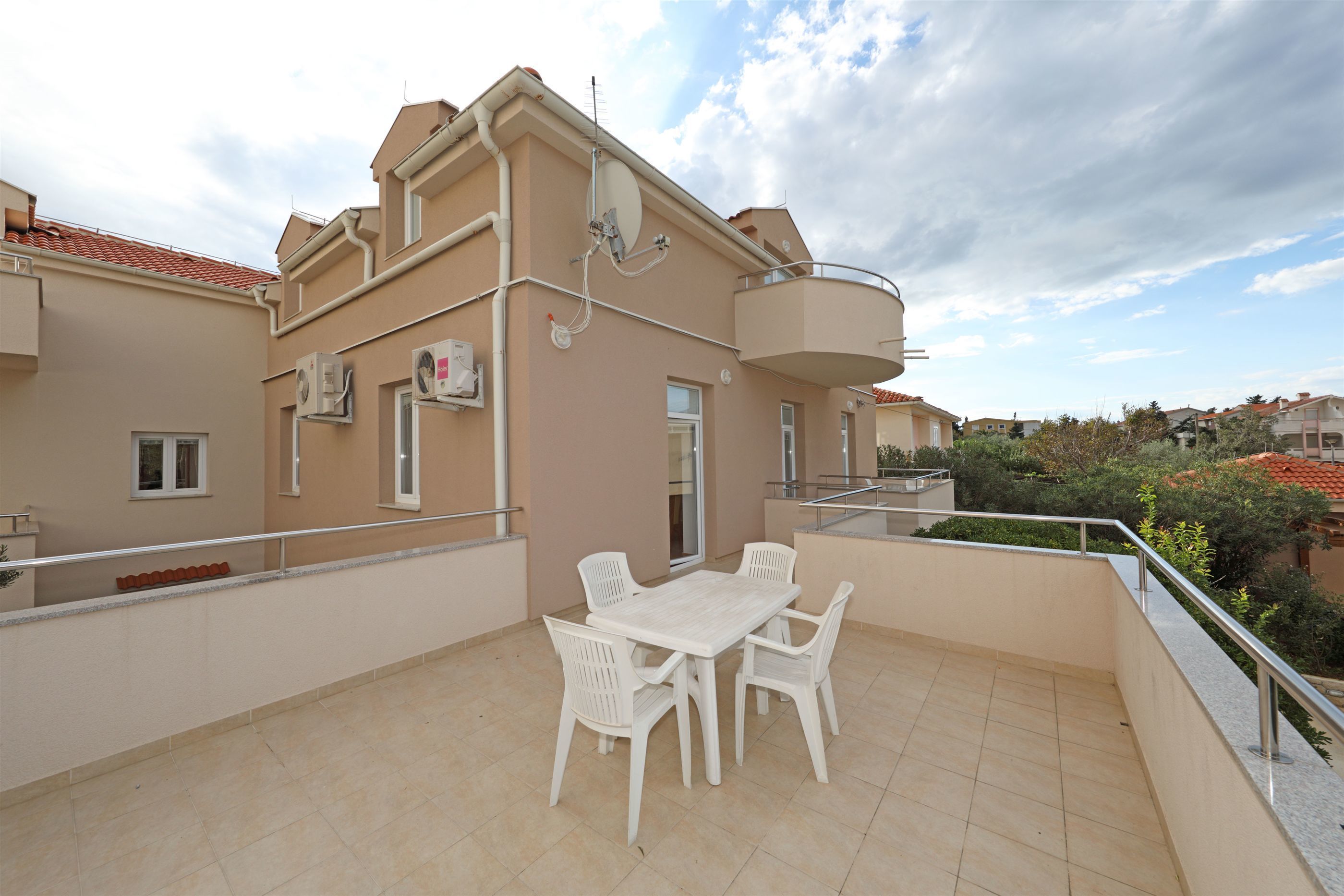 A balcony with a white table and chairs, a small window, and a door.