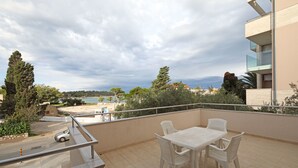 Ein Balkon mit Tisch und Stühlen mit Blick auf Strand und Bäume.