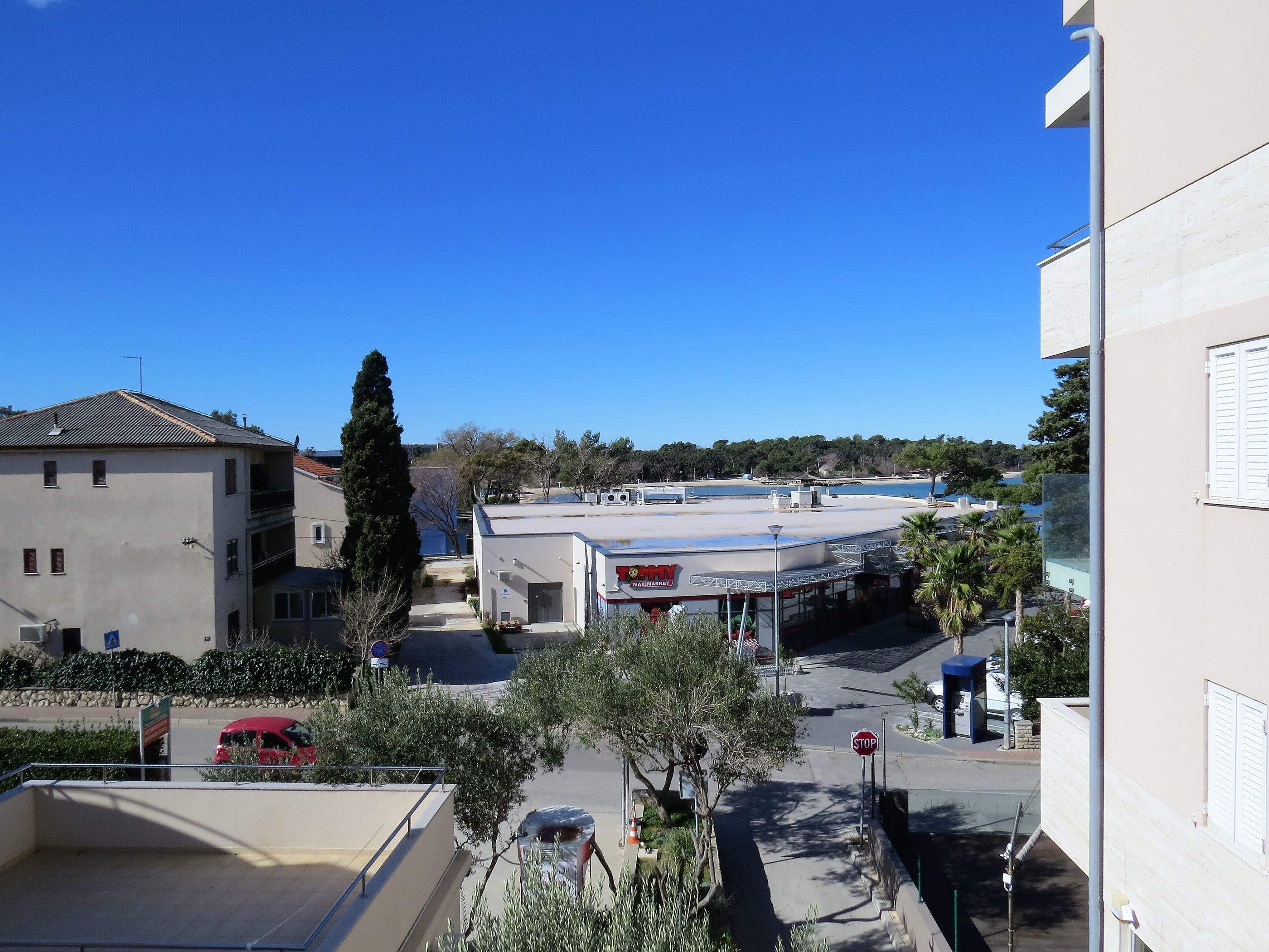 A view of a commercial building with a flat roof, a stop sign, and a clear blue sky.