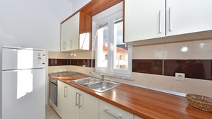 Eine moderne Küche mit weißen Schränken, einer Holz Arbeitsplatte, Edelstahlgeräten und einem Fenster mit Blick auf Gebäude.