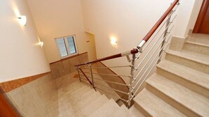 A staircase with a wooden handrail and metal balusters, leading to a landing with a window with blinds. - Apartment Lavanda (Rogoznica)