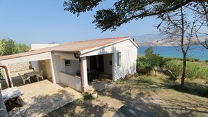 A small house with a stone patio, outdoor seating, and a view of the sea. - Apartment Marija (Kolan)
