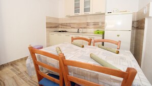 A compact kitchen with a dining table, chairs, and a refrigerator. - Apartment Marija (Kolan)
